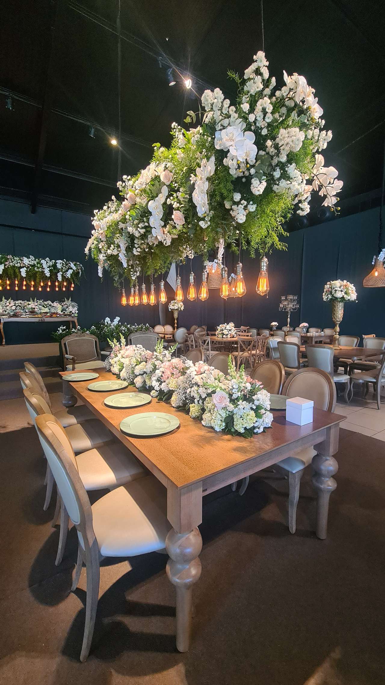 Salão decorado com mesas longas e arranjos florais